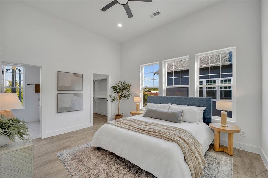 Bedroom featuring light hardwood / wood-style flooring, a towering ceiling, and ceiling fan