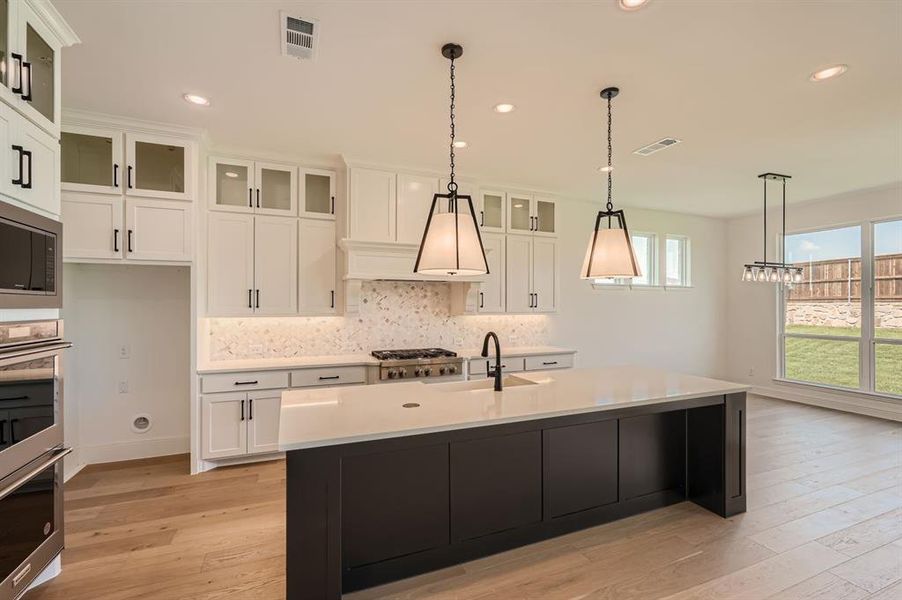 Kitchen featuring white cabinets, a kitchen island with sink, stainless steel appliances, light hardwood / wood-style floors, and sink