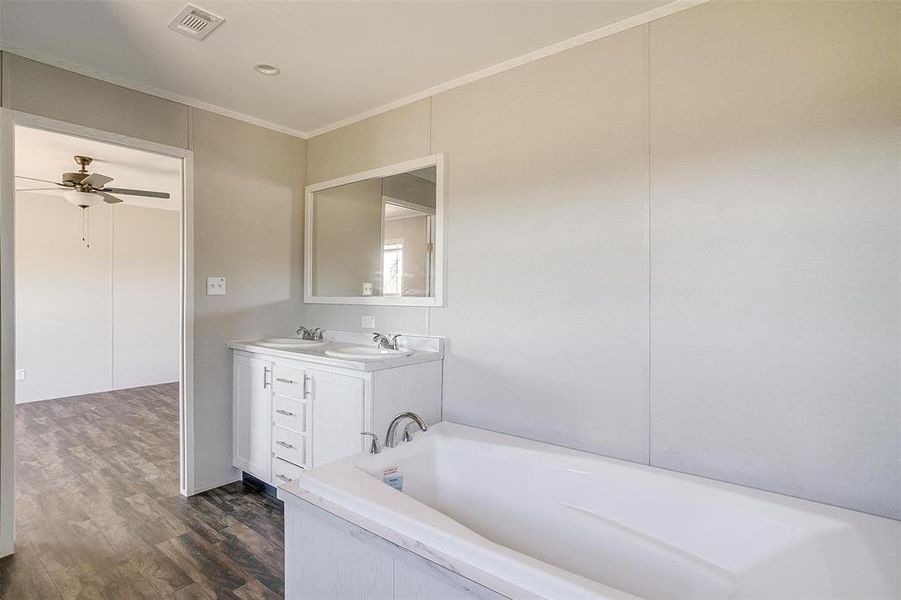 Bathroom with crown molding, vanity, a washtub, ceiling fan, and hardwood / wood-style flooring