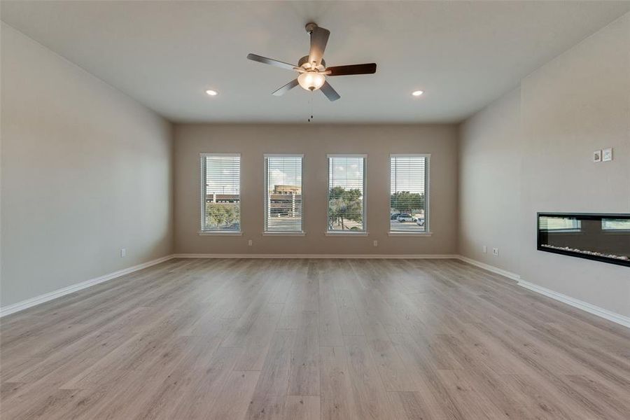 Unfurnished living room with a wealth of natural light, light wood-type flooring, and ceiling fan