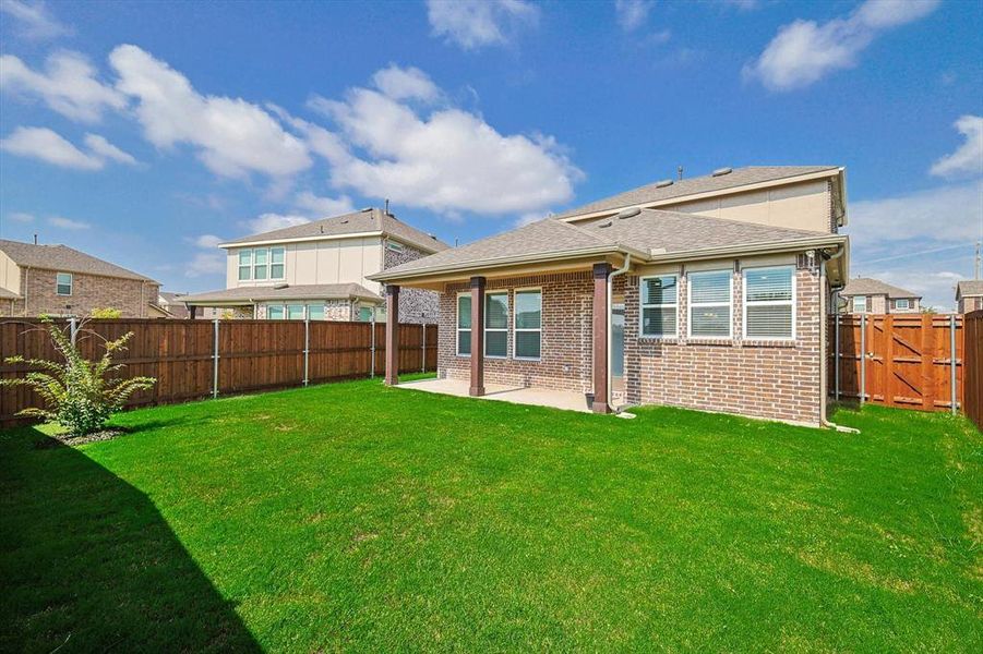 Rear view of house featuring a lawn and a patio