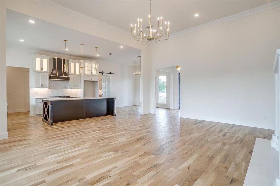 Kitchen with premium range hood, light hardwood / wood-style flooring, a barn door, and white cabinets