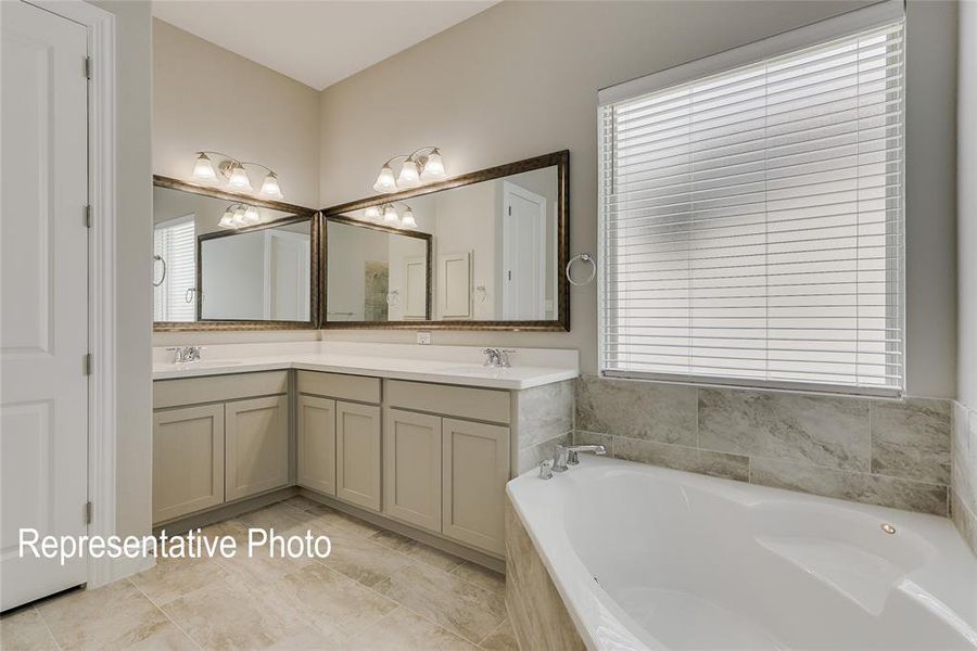 Bathroom with tile patterned floors, plenty of natural light, vanity, and a relaxing tiled tub