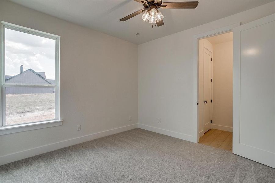 Empty room featuring light colored carpet and ceiling fan