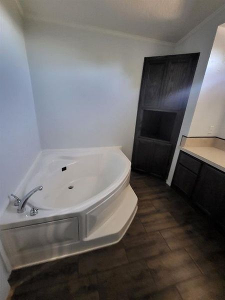 Bathroom with hardwood / wood-style floors, a bathtub, ornamental molding, and vanity