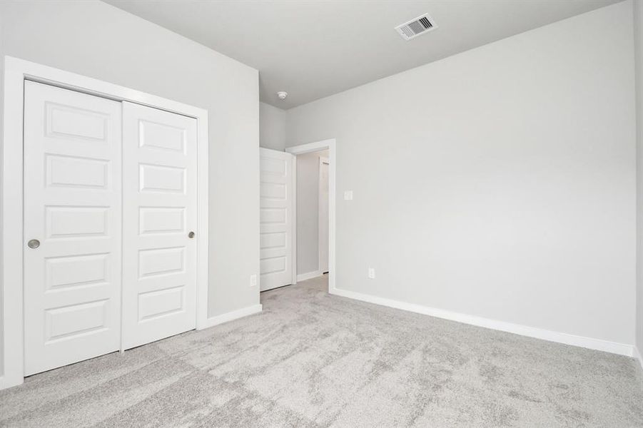 Secondary bedroom features plush. Sample photo of completed home with similar plan. Actual color and selections may vary. carpeting, large windows that let in plenty of natural light, bright paint, and spacious closets.