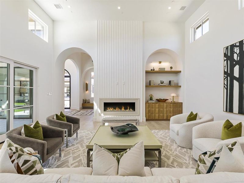 Living room with light hardwood / wood-style flooring, a towering ceiling, a fireplace, and built in features