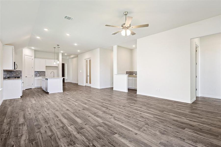 Unfurnished living room featuring ceiling fan, sink, and dark hardwood / wood-style flooring