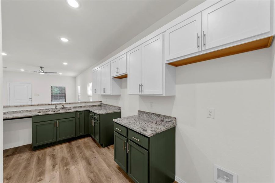 Kitchen with sink, green cabinetry, light wood-type flooring, white cabinetry, and ceiling fan