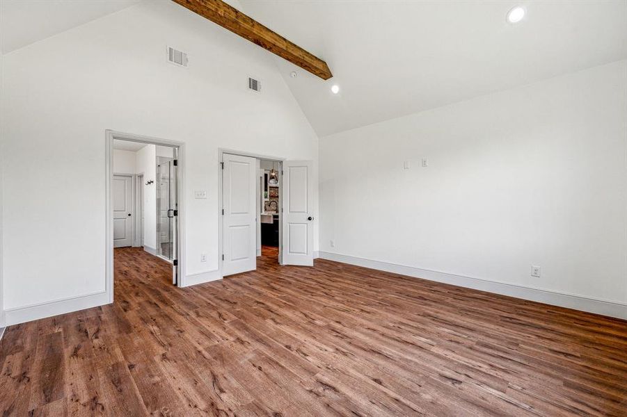 Unfurnished bedroom featuring beam ceiling, hardwood / wood-style flooring, and high vaulted ceiling