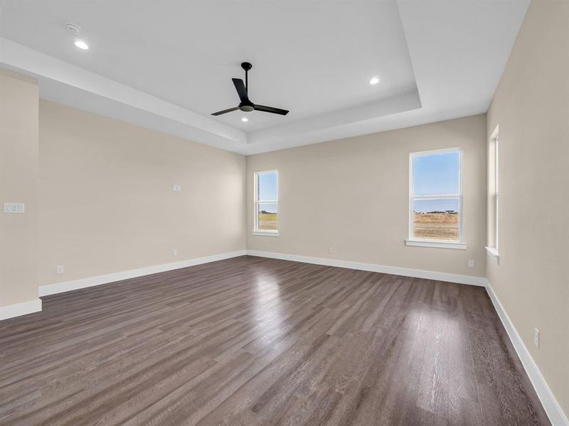 Empty room featuring ceiling fan, a tray ceiling, and dark hardwood / wood-style flooring