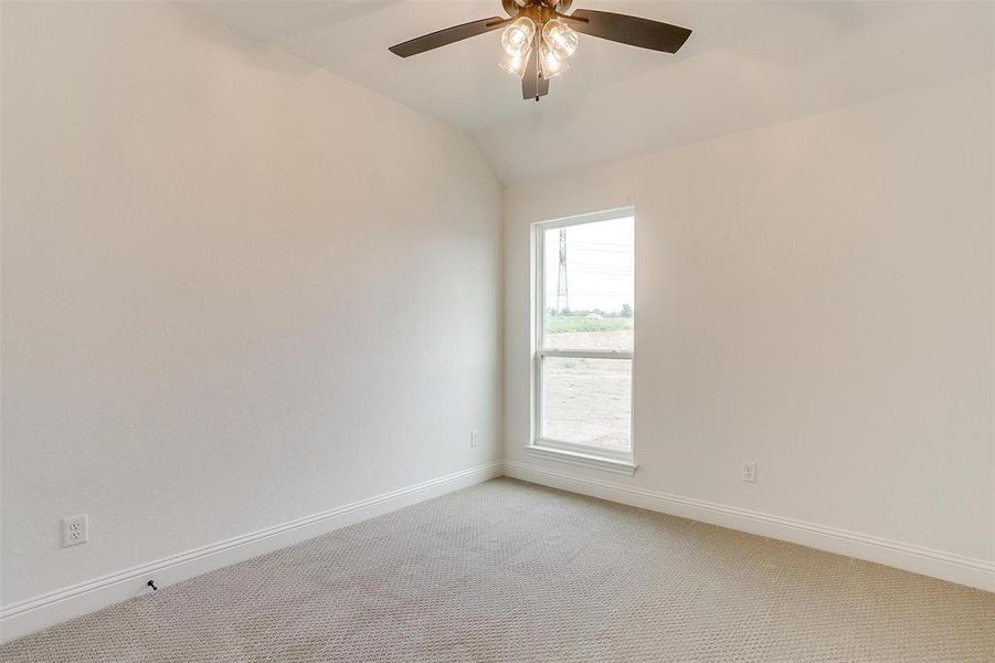 Carpeted empty room with ceiling fan and lofted ceiling