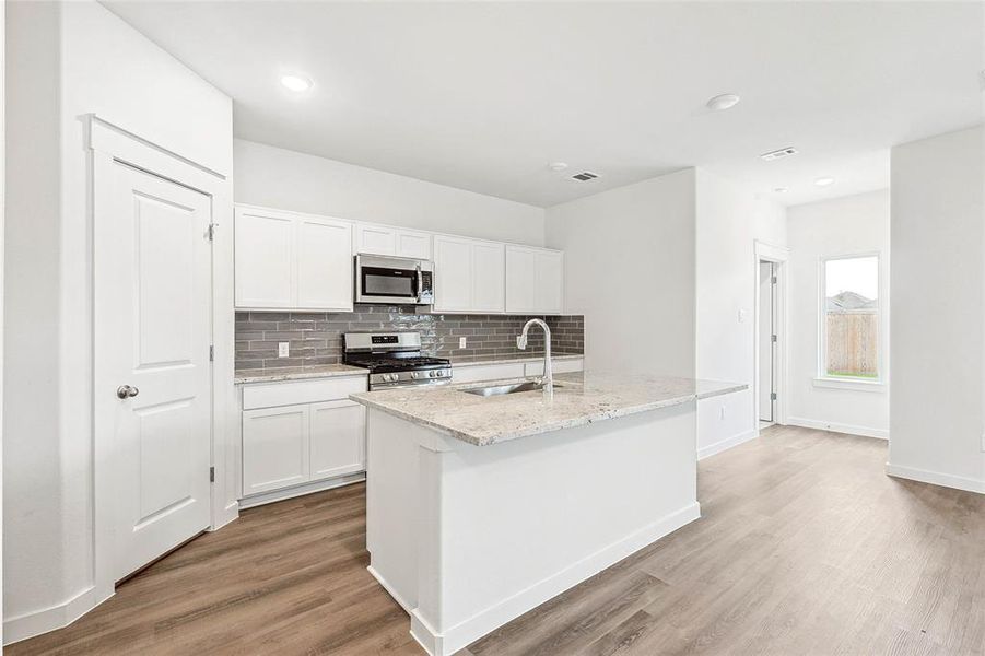 Kitchen with white cabinetry, tasteful backsplash, stainless steel appliances, light hardwood / wood-style floors, and sink