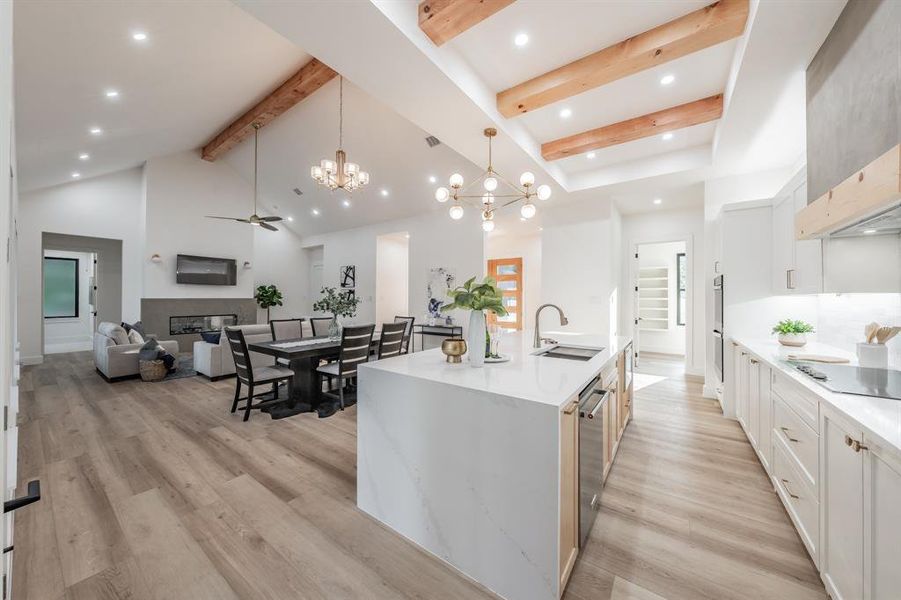 Kitchen featuring white cabinetry, blonde plank, wood-like luxury vinyl floors., ceiling fan with notable chandelier, high vaulted ceiling, and sink