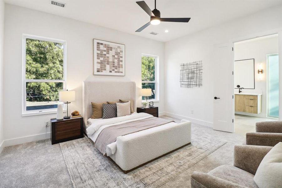 Carpeted bedroom with ceiling fan, multiple windows, and ensuite bath