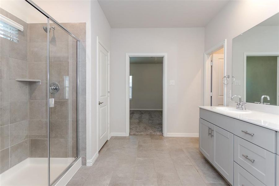 Primary bathroom featuring vanity, a shower with door, and tile patterned floors