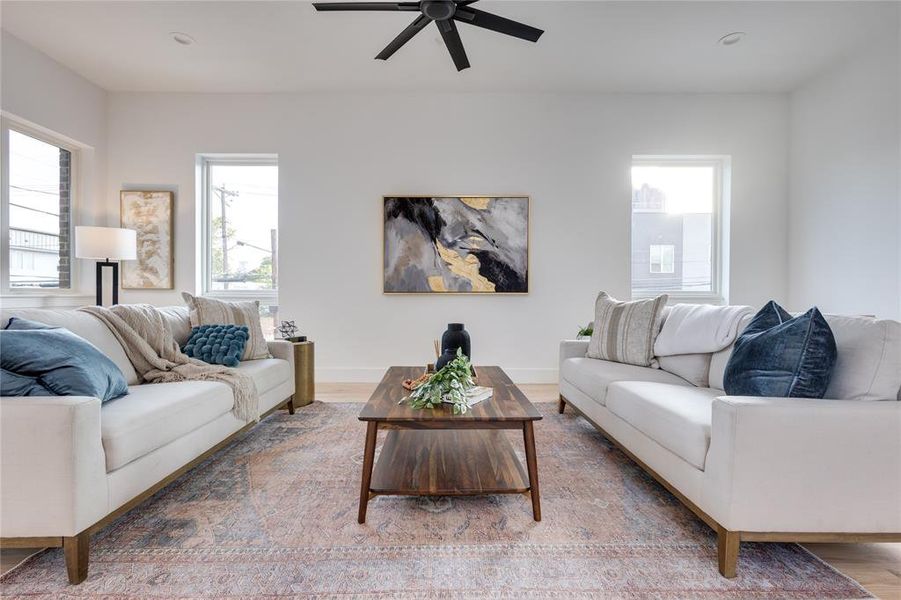 Living room with wood-type flooring, ceiling fan, and a healthy amount of sunlight