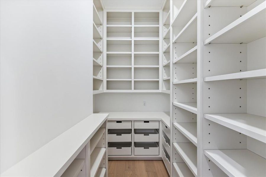 PANTRY: Floor-to-ceiling shelving lines the walls, offering abundant space to store pantry staples, cookware, and kitchen gadgets with ease. Custom cabinetry and pull-out drawers provide additional storage options, ensuring that everything is neatly tucked away and easily accessible whenever inspiration strikes.