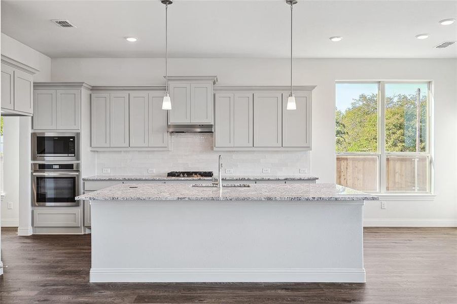 Kitchen featuring appliances with stainless steel finishes, light stone countertops, dark hardwood / wood-style flooring, and sink