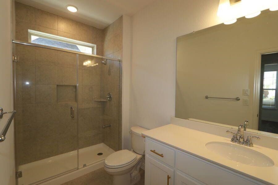 Bathroom featuring toilet, vanity, and an enclosed shower