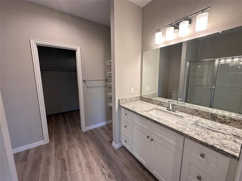 Bathroom with a shower with door, vanity, and wood-type flooring