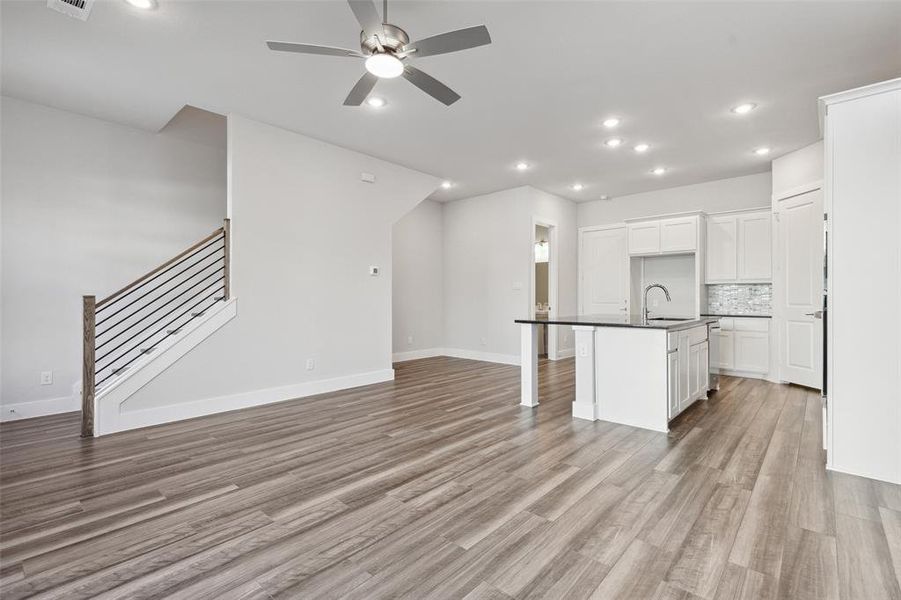 Unfurnished living room with ceiling fan, sink, and light hardwood / wood-style floors