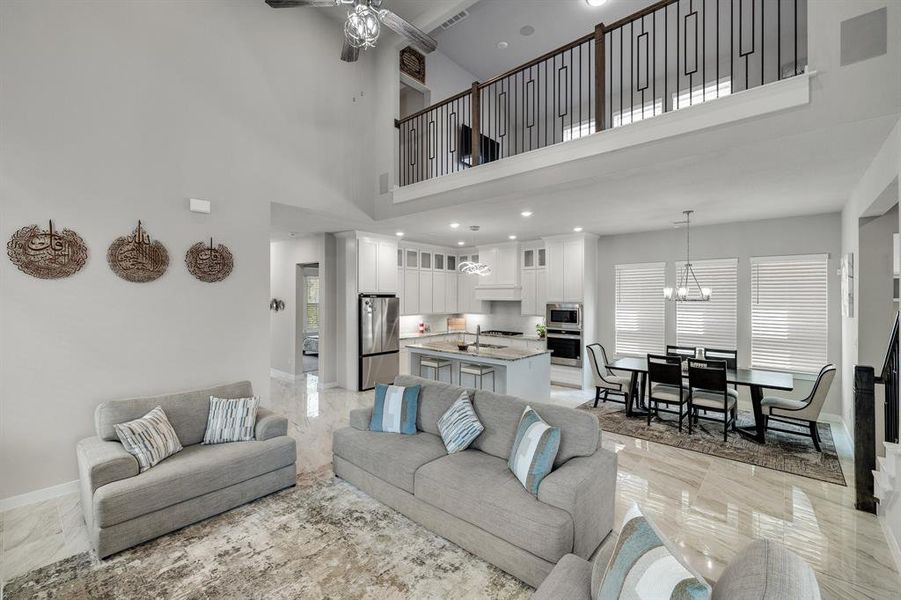 Living room featuring a high ceiling, sink, ceiling fan with notable chandelier, and light tile patterned floors