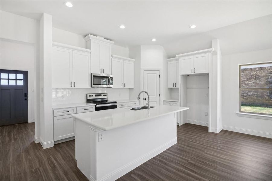 Kitchen featuring dark wood-type flooring, a kitchen island with sink, sink, white cabinets, and stainless steel appliances