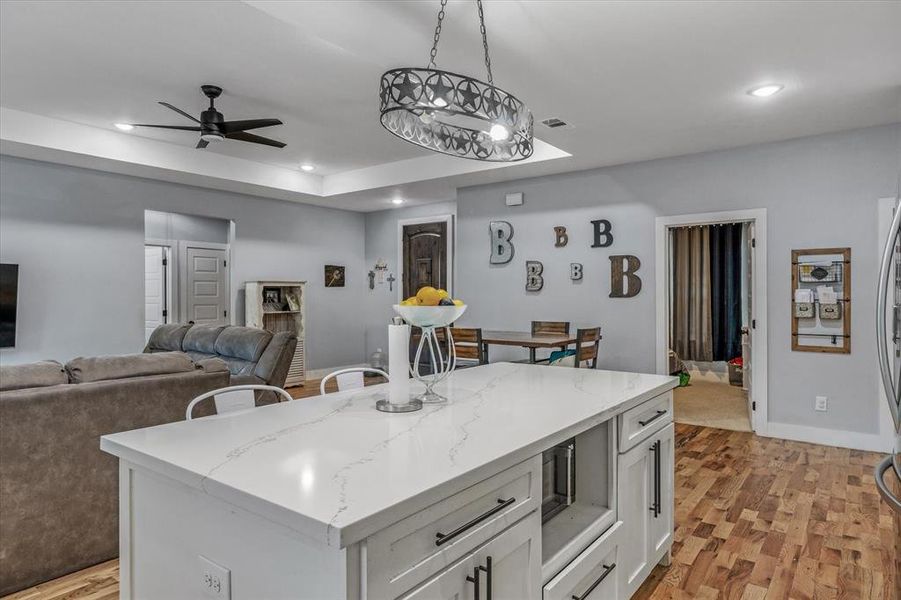 Kitchen with pendant lighting, light hardwood, white cabinetry, and a kitchen island