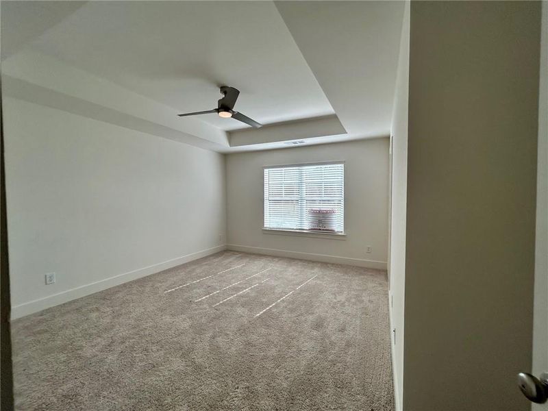 Unfurnished room with a tray ceiling, ceiling fan, and light colored carpet