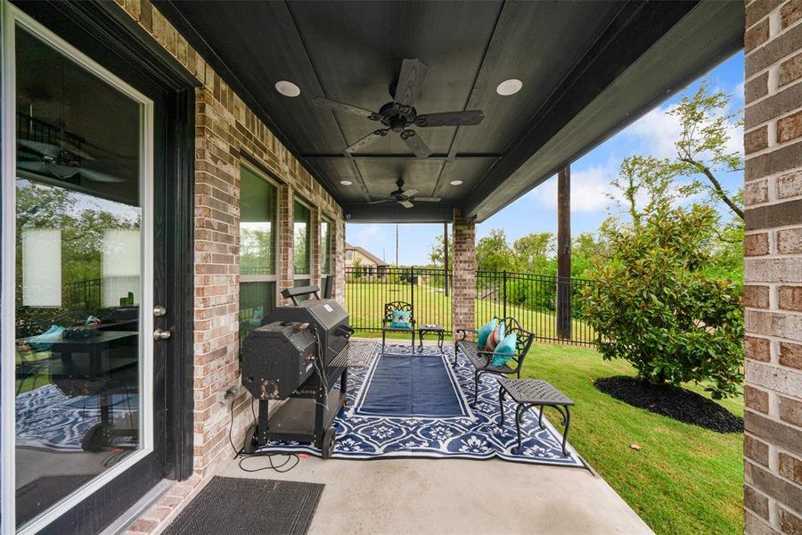 Spacious covered patio with ceiling fan which is perfect for relaxation and outdoor dining. The iron fence makes the backyard space feel so much larger!