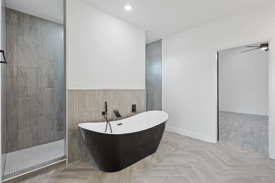 Bathroom featuring ceiling fan, shower with separate bathtub, tile walls, and parquet flooring