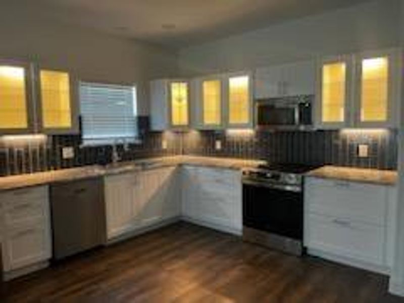 Kitchen with stainless steel electric range oven, dark hardwood / wood-style floors, and white cabinetry