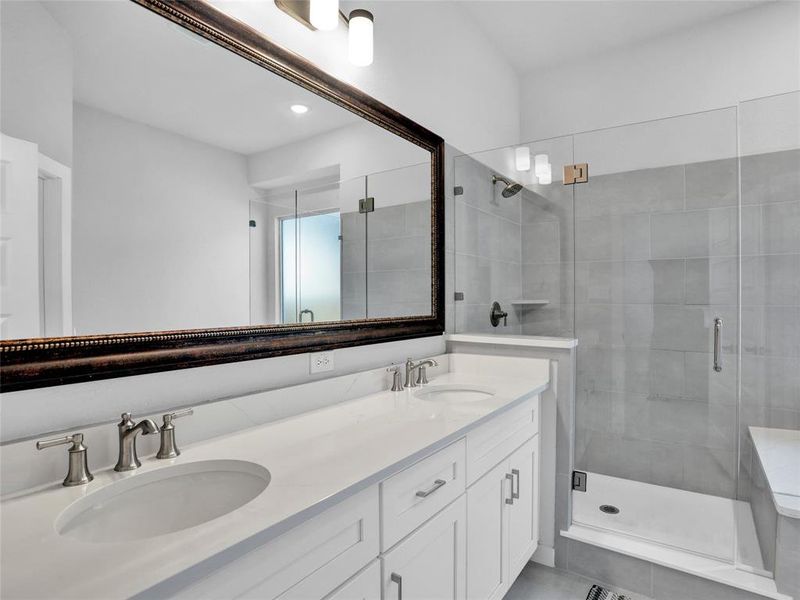 Primary bathroom suite with dual vanities, quartz counters, frameless walk in shower, and garden bath.