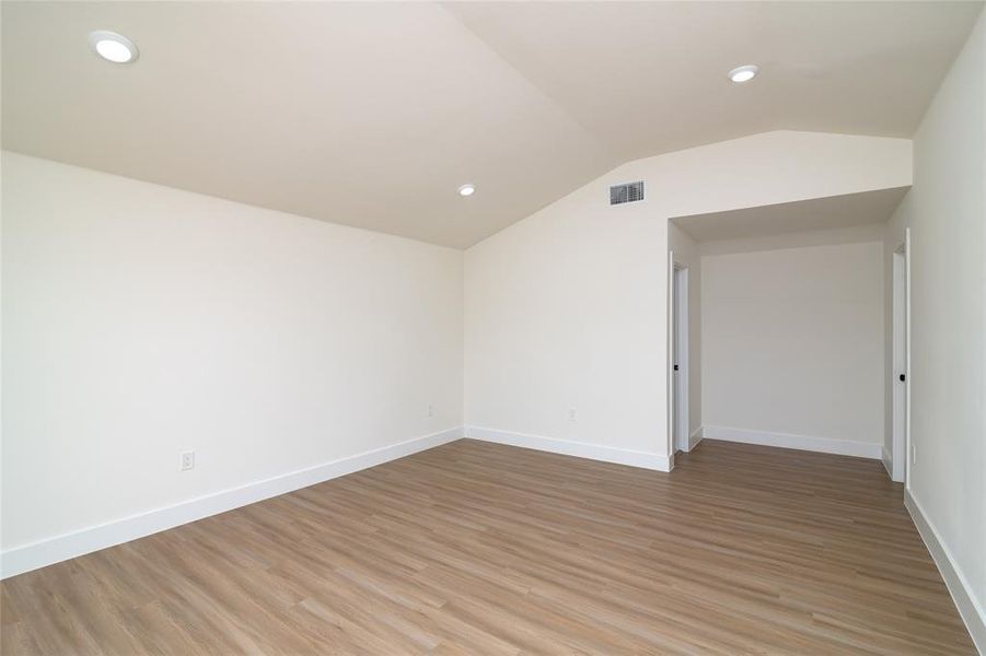 Unfurnished room with light hardwood / wood-style floors and lofted ceiling