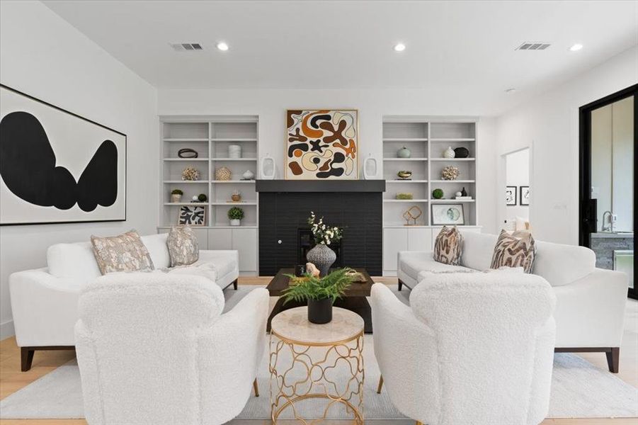 Living room featuring light wood-type flooring, a fireplace, and built in features