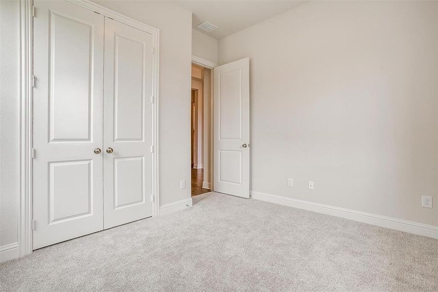 Unfurnished bedroom with light carpet and a closet