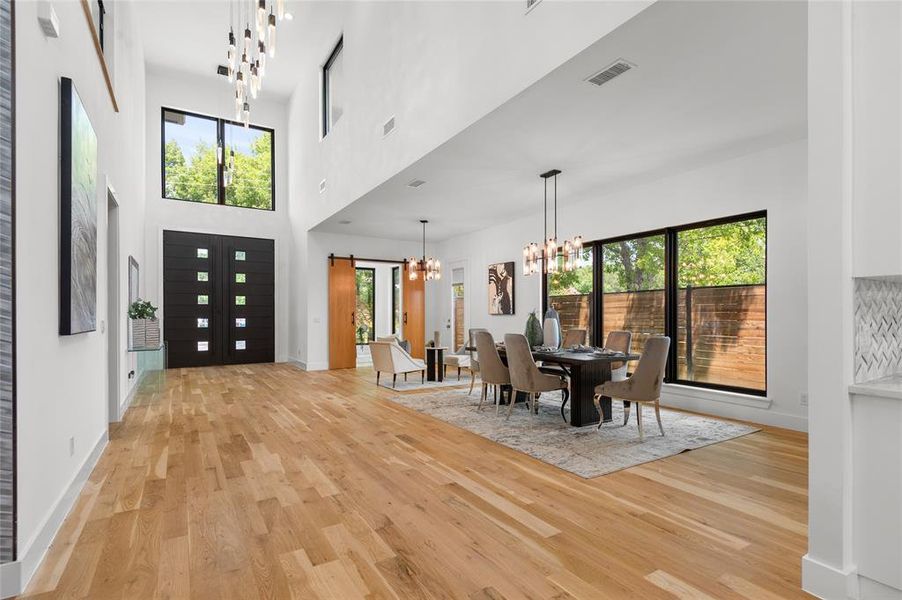 Foyer featuring a towering ceiling, an inviting chandelier, light wood-type flooring, and plenty of natural light