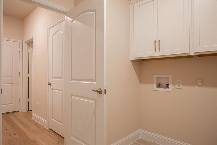 Laundry area featuring light hardwood / wood-style floors, hookup for a washing machine, and cabinets