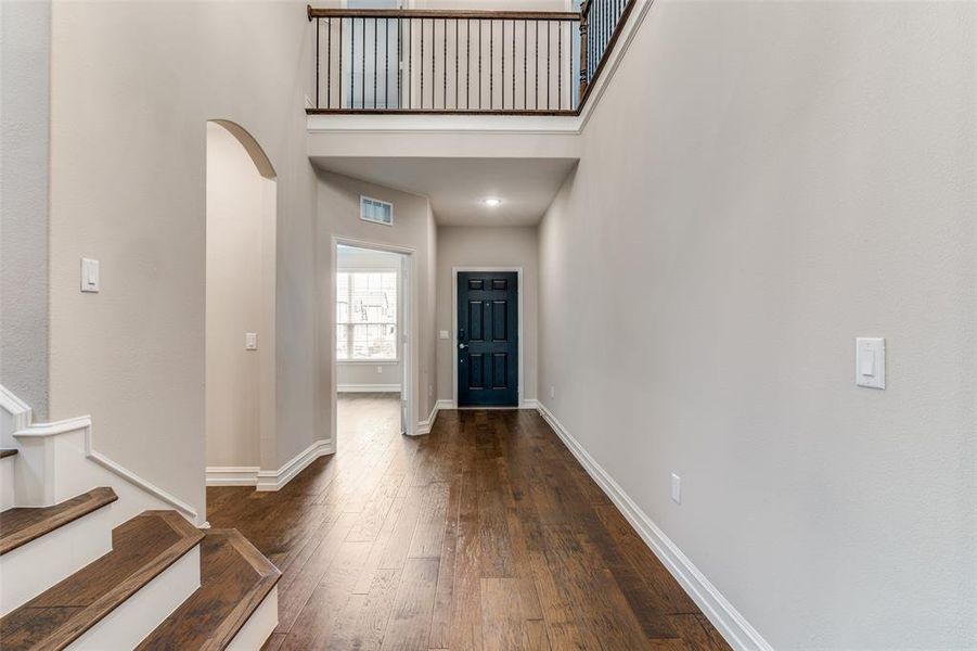 Foyer with dark wood-type flooring and a towering ceiling