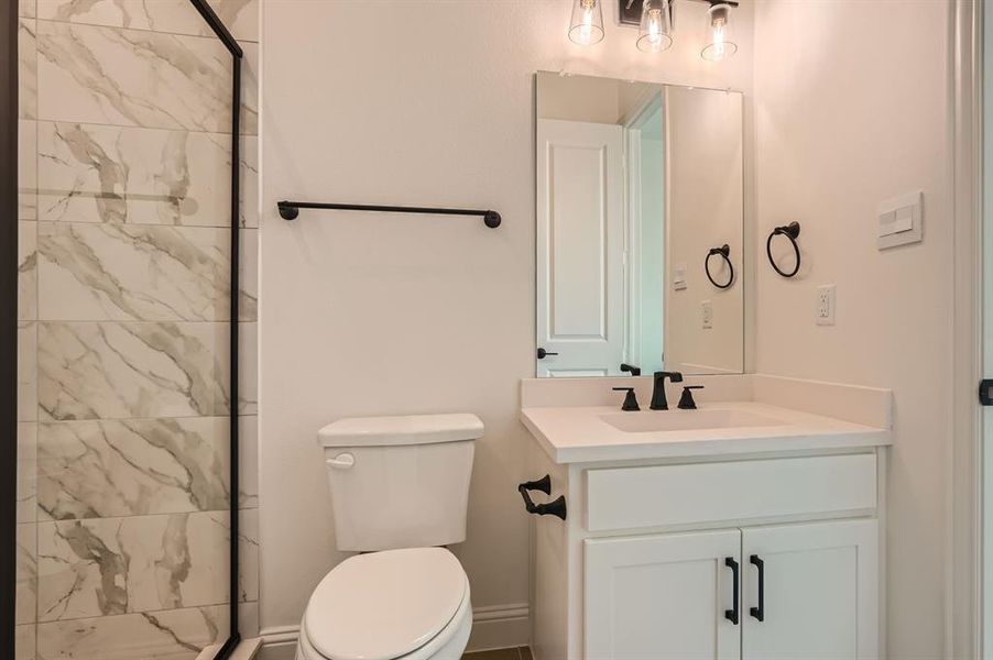 Bathroom featuring toilet, vanity, and an enclosed shower