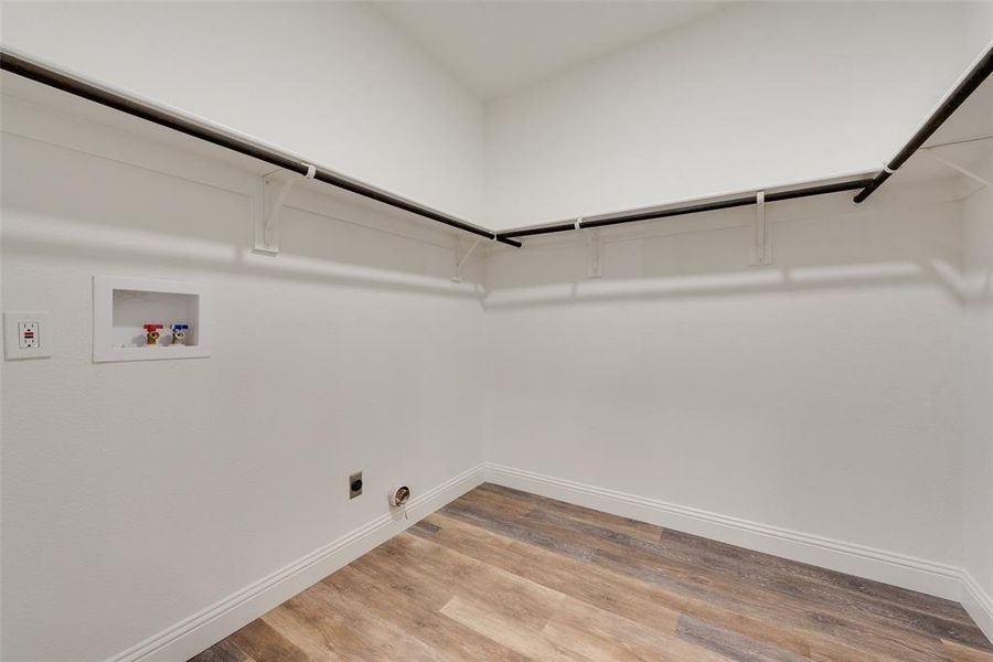 Clothes washing area with hookup for an electric dryer, hardwood / wood-style floors, hookup for a washing machine, and gas dryer hookup