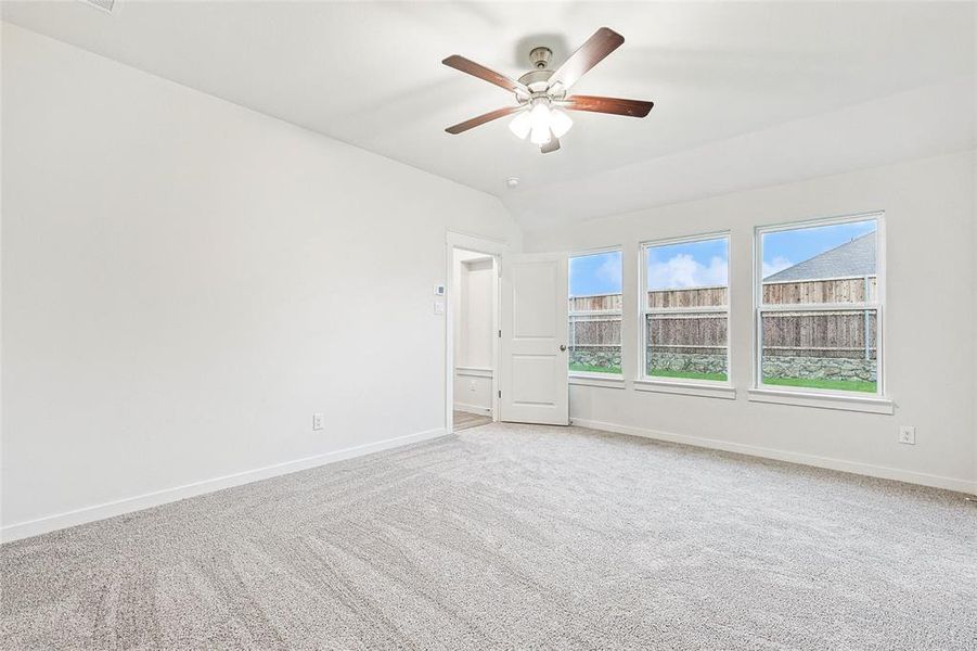 Carpeted empty room featuring vaulted ceiling and ceiling fan