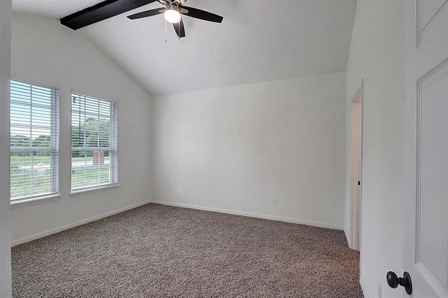 Carpeted empty room with lofted ceiling with beams and ceiling fan