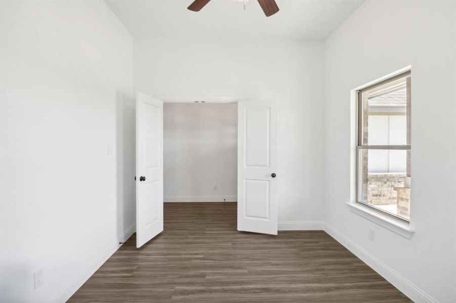 Unfurnished bedroom featuring ceiling fan, multiple windows, and dark wood-type flooring