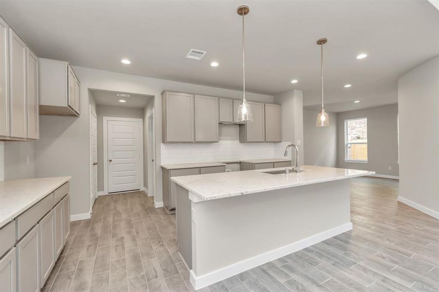 The kitchen is a culinary haven, featuring granite countertops, a tile backsplash, stainless steel appliances, 42” upper cabinets, and undercabinet lighting. Sample photo of completed home with similar floor plan. As-built interior colors and selections may vary.