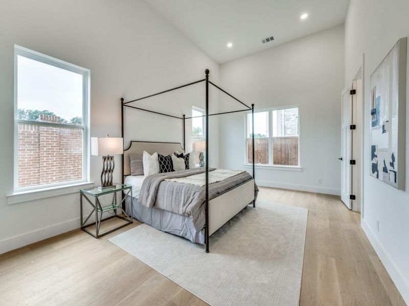 Bedroom with light wood-type flooring and high vaulted ceiling