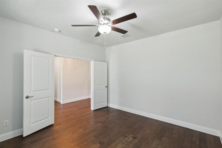 Unfurnished bedroom featuring dark wood-type flooring and ceiling fan