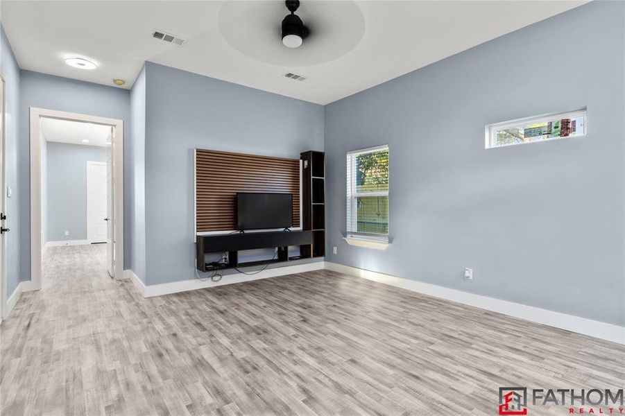 Unfurnished living room with ceiling fan and light wood-type flooring