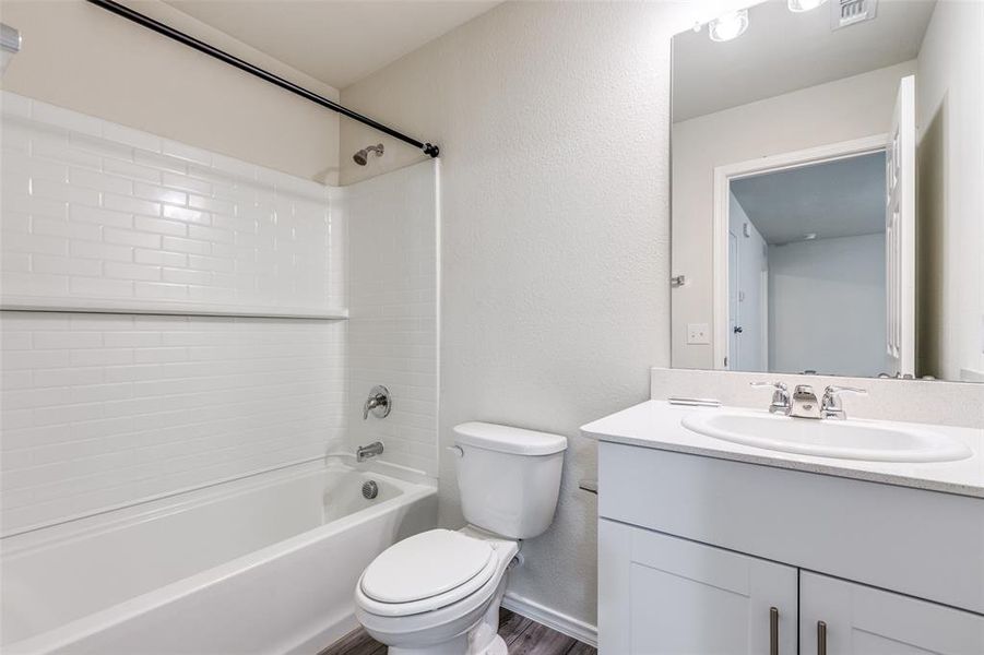 Full bathroom featuring hardwood / wood-style flooring, toilet, vanity, and shower / tub combination